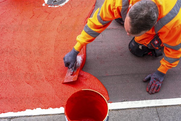Application of red road surfacing on a cycle lane, inner-city road, so-called cold plastic