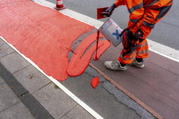 Application of red road surfacing on a cycle lane, inner-city road, so-called cold plastic