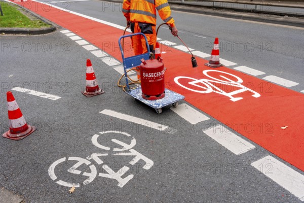 Application of red road surfacing on a cycle lane, inner-city road, so-called cold plastic