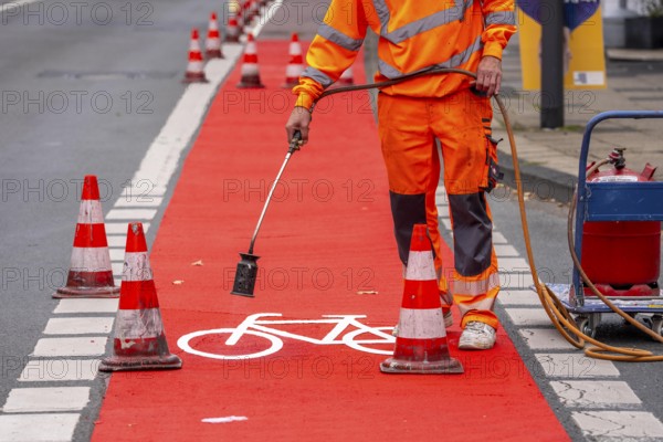 Application of red road surfacing on a cycle lane, inner-city road, so-called cold plastic