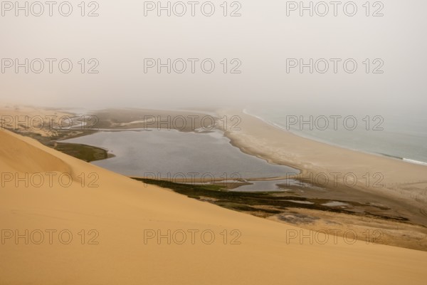 Golden dunes and the Atlantic Ocean near Namib-Naukluft Park, Namibia. A lagoon and shoreline fade