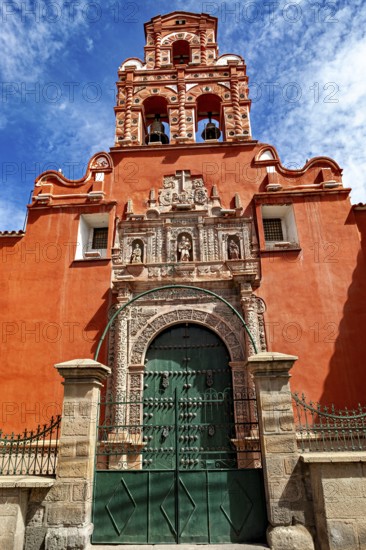 Door of a colonial building with red façade and bell tower under a clear blue sky, The churches of