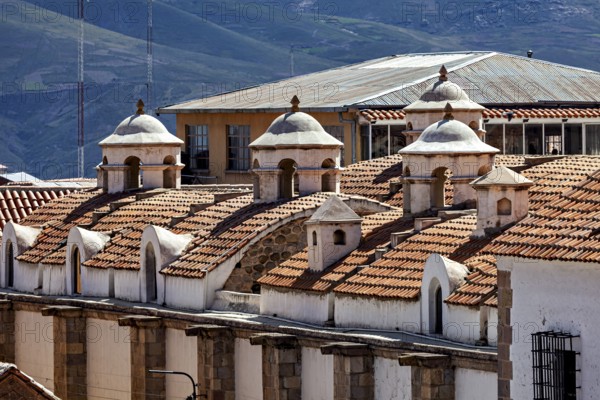 Close-up of building roofs with characteristic small domes and mountain scenery in the background,