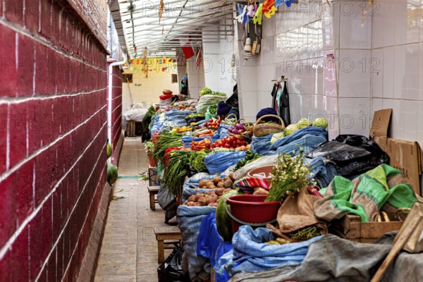 A covered market aisle full of colourful vegetables and spices in a tight arrangement, market stall