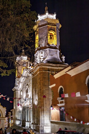 Illuminated church at night, decorated with flags and surrounded by trees, The churches of the city