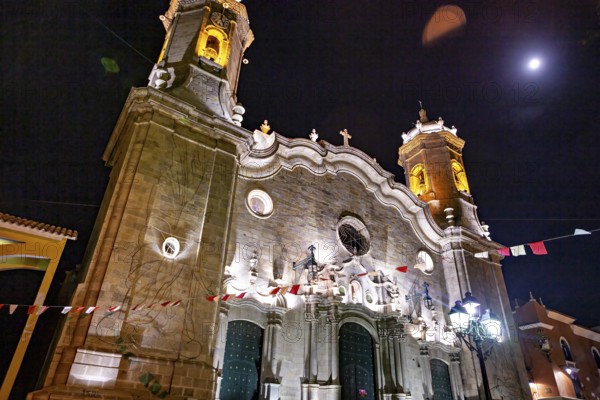 Illuminated church under the night sky with festive lights and flags, The churches of the city of