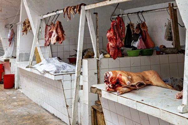 A rustic market stall with raw meat hanging on tiled walls, The meat market in the market halls of