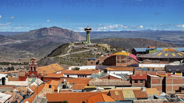 View of orange roofs with a modern building and an antenna in a mountainous environment, view over