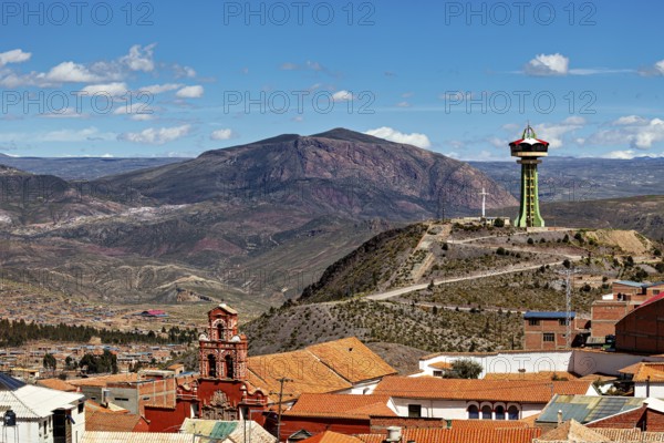 City with red roofs and observation tower, surrounded by mountains under a blue sky, The water