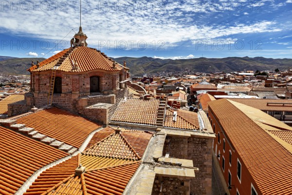 Colonial building with traditional roof tiles and mountain backdrop under a blue sky, The roof of