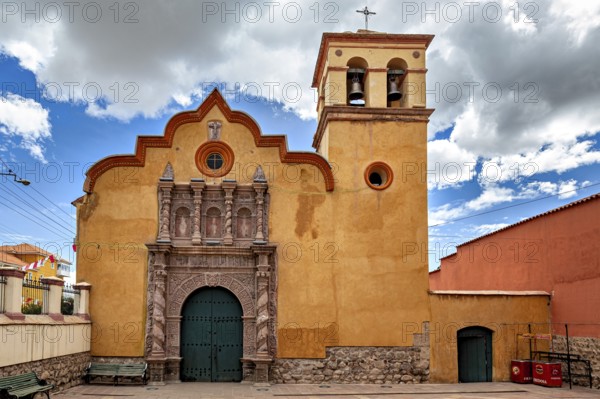 Colonial church with baroque bell tower and impressive wooden gate under a dramatic sky, The old