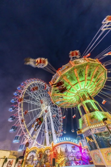 Folk festival time in Stuttgart. Ferris wheel and chain carousel in the evening. The 178th