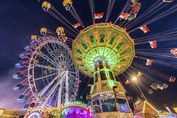 Folk festival time in Stuttgart. Ferris wheel and chain carousel in the evening. The 178th