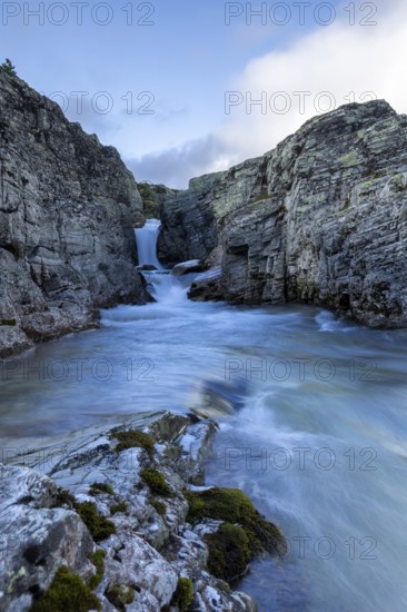 A river flows through a narrow gorge, over a small waterfall, surrounded by steep cliffs, Peer Gynt