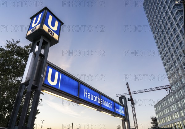 The picture shows a modern high-rise building in Berlin and a striking underground station sign