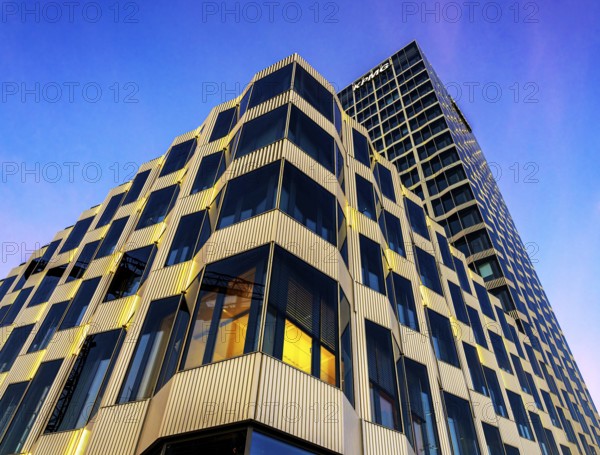 The picture shows a modern office and commercial building at the central station, warm evening