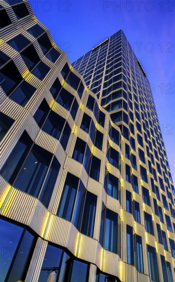 The picture shows a modern office and commercial building at the central station, warm evening