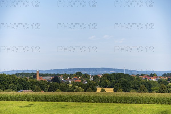 A rural view of a village surrounded by fields and trees under a blue sky, Bielefeld, Westphalia,