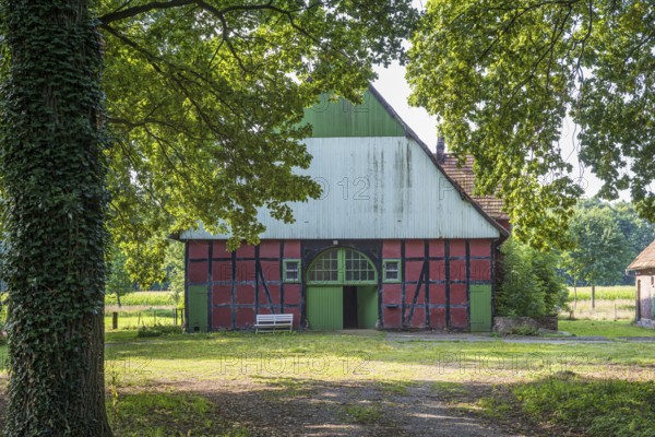 A rustic half-timbered barn with open Tor tor, surrounded by trees and nature, Gütersloh,