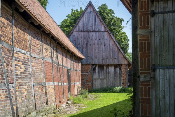 Half-timbered buildings in a green courtyard on a sunny day, Weser cycle path, Schlüsselburg barn