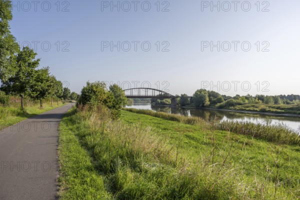 An idyllic river with a bridge surrounded by a green landscape under a clear sky, Weser, Weser