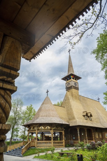 Remarkable wooden church with intricate carvings and a rustic roof against a cloudy sky, the