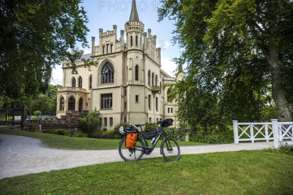 A Gothic castle with a bicycle on a path in idyllic surroundings, Evenburg Castle, Leer, East
