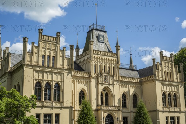 An imposing castle with Gothic elements and large windows under a blue sky, Schloss Evenburg, Leer,