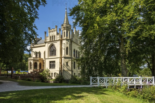 A castle in a peaceful landscape with a bridge in the foreground and a blue sky, Schloss Evenburg,