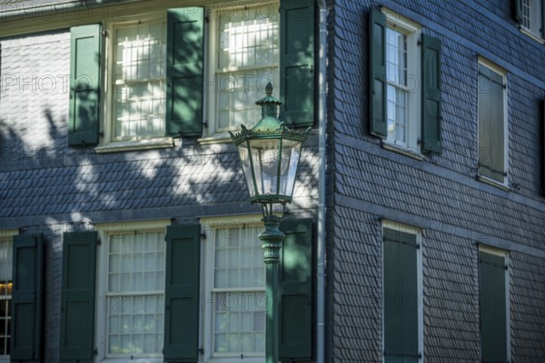Side view of a building with green shutters, old lantern and shadow play, Friedrich Engels House in