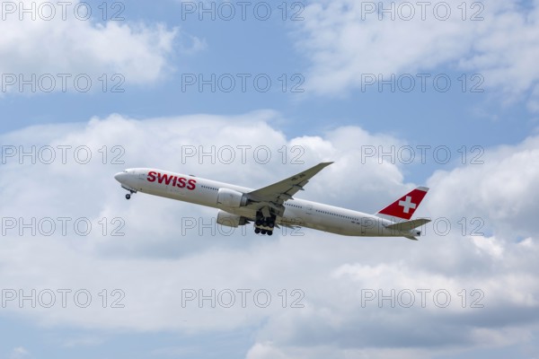 Swiss Airlines Passenger Airplane Flying Against Blue Sky and Clouds in a Sunny Summer Day From the