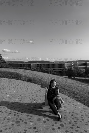 Nature Park with Panoramic View and Modern Building and a Woman Sitting on a Chair in a Sunny