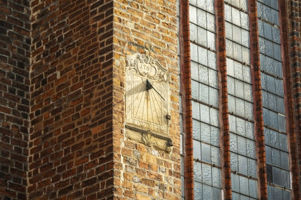 Sundial on a red brick wall next to large Gothic windows, cathedral, Verden an der Aller, Lower