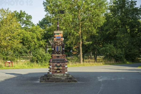 Colourful brick sculpture in a park with green trees in the background in the afternoon, Bücken,