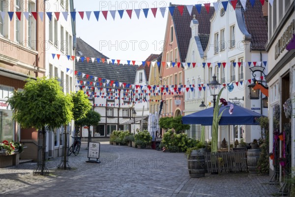 Colourfully decorated street in an old town with garlands and plants along the pavements,