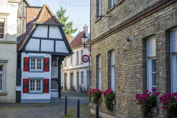 Small half-timbered house in narrow street decorated with flowers, historic surroundings,