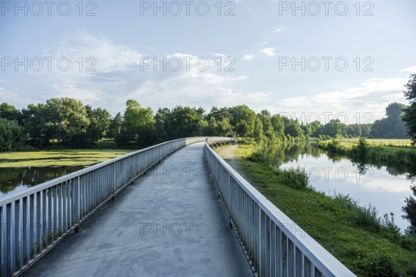 Bridge along a quiet river, green surroundings and blue sky reflected in the water, Emssee near