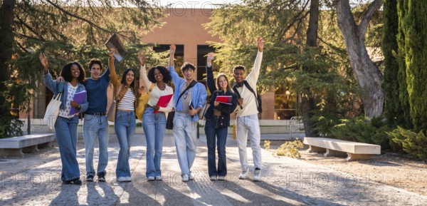 Group of young, happy, diverse university students standing together, raising their hands in