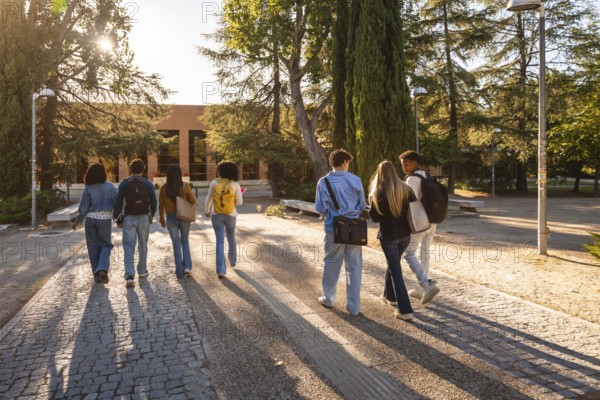 Young diverse students with backpacks walking together along a paved path, heading towards a