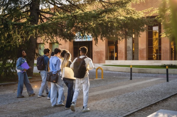 Group of diverse university students with backpacks and folders walking together on campus, heading