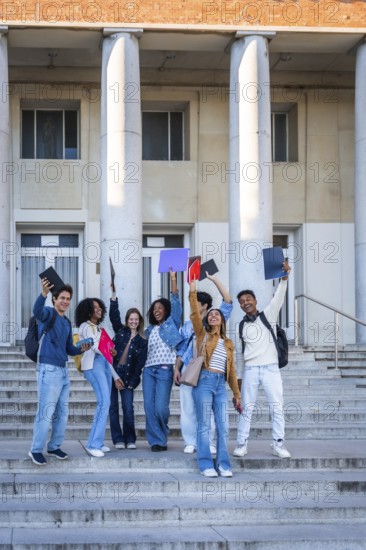 Diverse group of happy college students standing on the outdoor stairs of a university building,