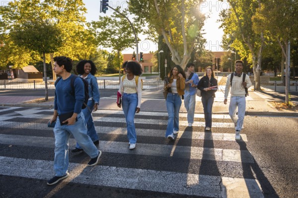 Group of multi ethnic university students walking together across a crosswalk on a sunny day,