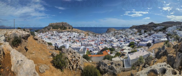 Panorama of the town of Lindos with Acropolis with white buildings by the sea under a blue sky,