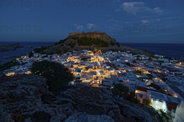 Picturesque Lindos with the ancient Acropolis at dusk with glowing houses and castle in the