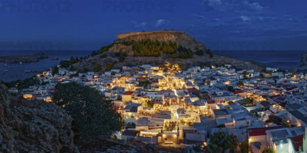 Illuminated town of Lindos with the ancient acropolis and sea in the background, surrounded by