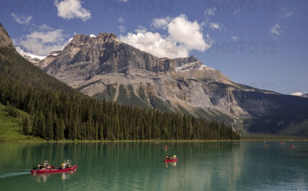 Canoes on Emerald Lake surrounded by forest and the Canadian Rocky Mountains under a clear sky