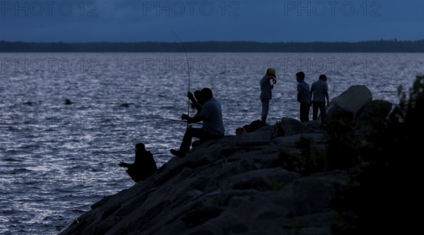 Group of people fishing at night, silhouetted against the water in Ottawa, Ontario, Canada, North