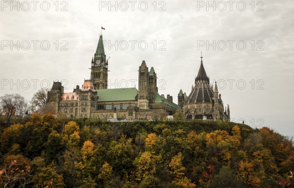 The Canadian Parliament building on a hill surrounded by colorful autumn trees, showcasing gothic