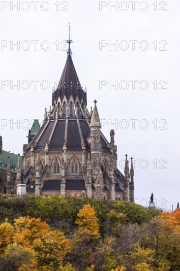 The stately Canadian Parliament Buildings with their Gothic structure with a tall spire and autumn