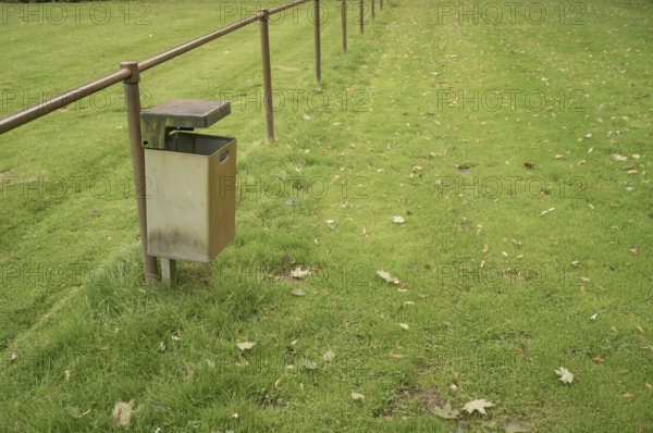 Borken, NRW, Germany, Empty metal garbage bin standing next to a railing in a public park with